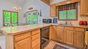 A kitchen with wooden cabinets, a built-in dishwasher, a microwave, and a red toaster. - Deck & Resort Amenities: Pocono Lake Home (Pocono Lake)