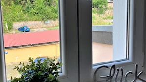 A window with a view of a residential area, a potted plant, and a 'Glück' sign on the sill. - Modern furnishings.  "Wanderfalke" Vacation Rental, Central & Quiet, 55 sqm, Shared Terrace (Königstein)
