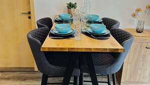 A dining table set with blue bowls and glasses, surrounded by dark upholstered chairs. - Modern furnishings.  "Wanderfalke" Vacation Rental, Central & Quiet, 55 sqm, Shared Terrace (Königstein)