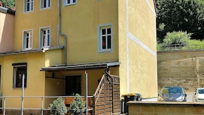 A multi-story yellow building with a balcony and potted plants. - Modern furnishings.  "Wanderfalke" Vacation Rental, Central & Quiet, 55 sqm, Shared Terrace (Königstein)