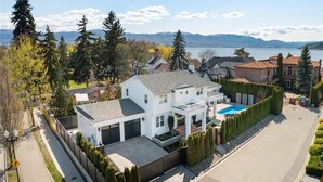 Ein zweigeschossiges Haus mit Garage, Swimmingpool und Blick auf einen See und Berge.