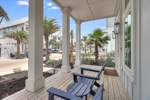A covered porch with wooden benches and palm trees.
