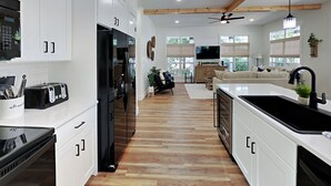 A modern kitchen with white cabinetry, a black refrigerator, and a built-in oven.