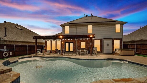 A large house with a swimming pool, outdoor seating, and a covered patio area.