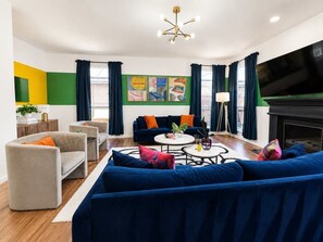 A modern living room with a blue sofa set, a coffee table, and a flat-screen TV.