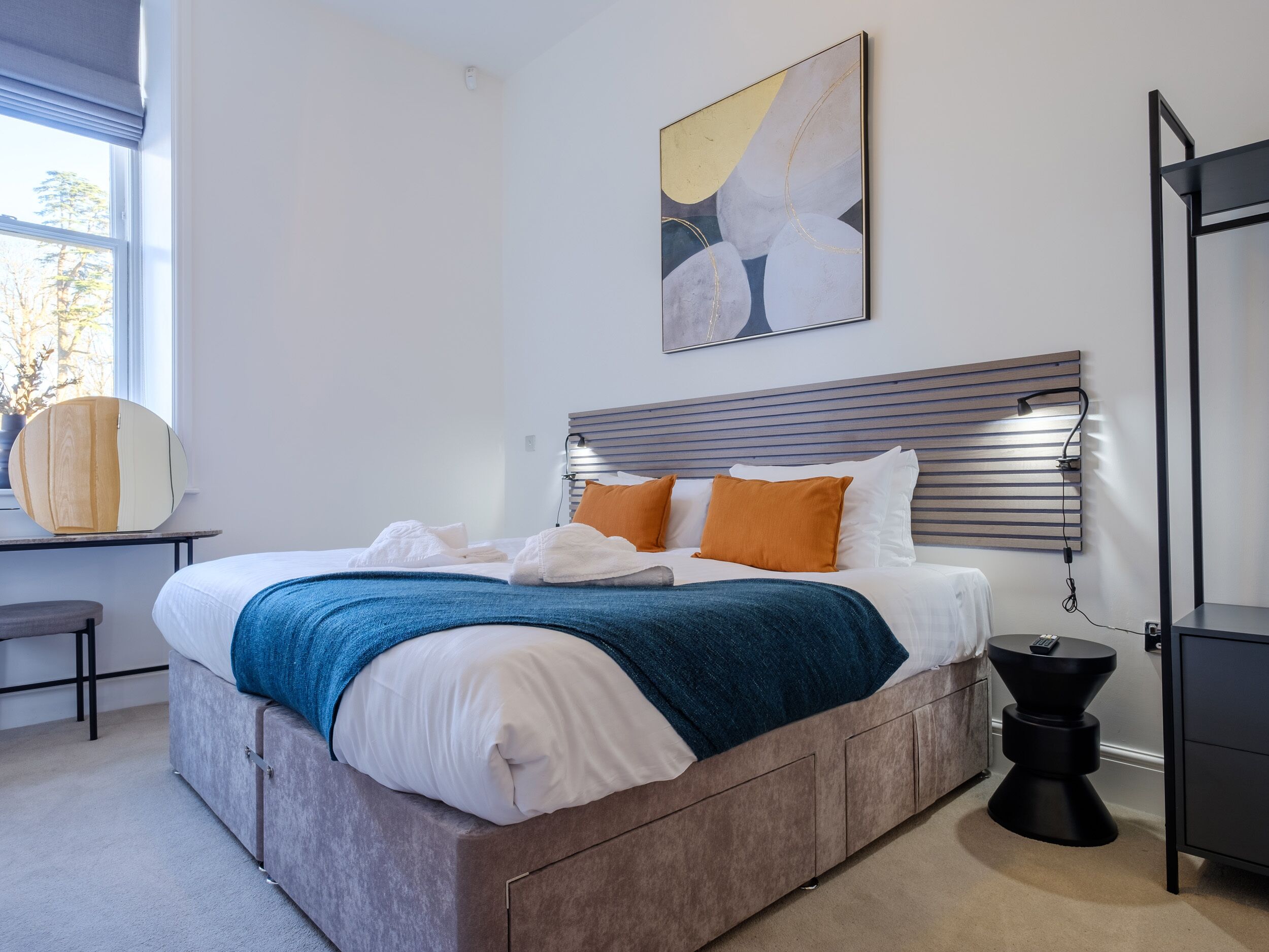 A modern bedroom with a bed, bedside table, and a wall-mounted artwork.