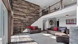 Un vaste espace de vie agrémenté d’un escalier en bois, de canapés en cuir et d’un grand tapis.