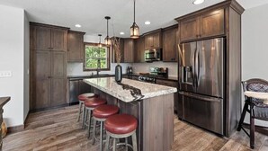 Une cuisine moderne avec des meubles en bois, des appareils en acier inoxydable et un îlot central doté de tabourets.