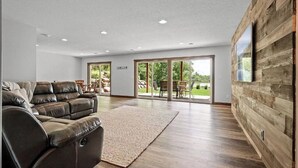 Un salon spacieux avec un canapé en cuir, une grande moquette et un mur décoratif en bois.