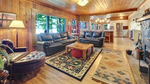 A spacious living room with leather sofas, a coffee table, and a fireplace. - South Arm of Lake Charlevoix  | Fire-pit | Private Dock | dog friendly (East Jordan)