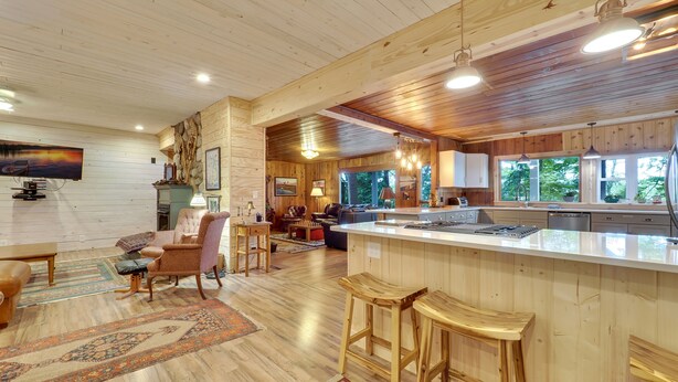 A spacious living area with a large TV, comfortable seating, and a wooden floor. - South Arm of Lake Charlevoix  | Fire-pit | Private Dock | dog friendly (East Jordan)