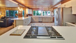 A modern kitchen with wooden cabinetry, a stainless steel stove, and a large island. - South Arm of Lake Charlevoix  | Fire-pit | Private Dock | dog friendly (East Jordan)