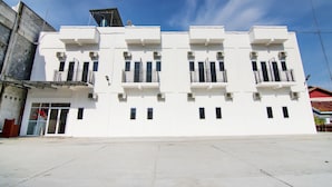 Un edificio blanco con varios balcones y unidades de aire acondicionado.