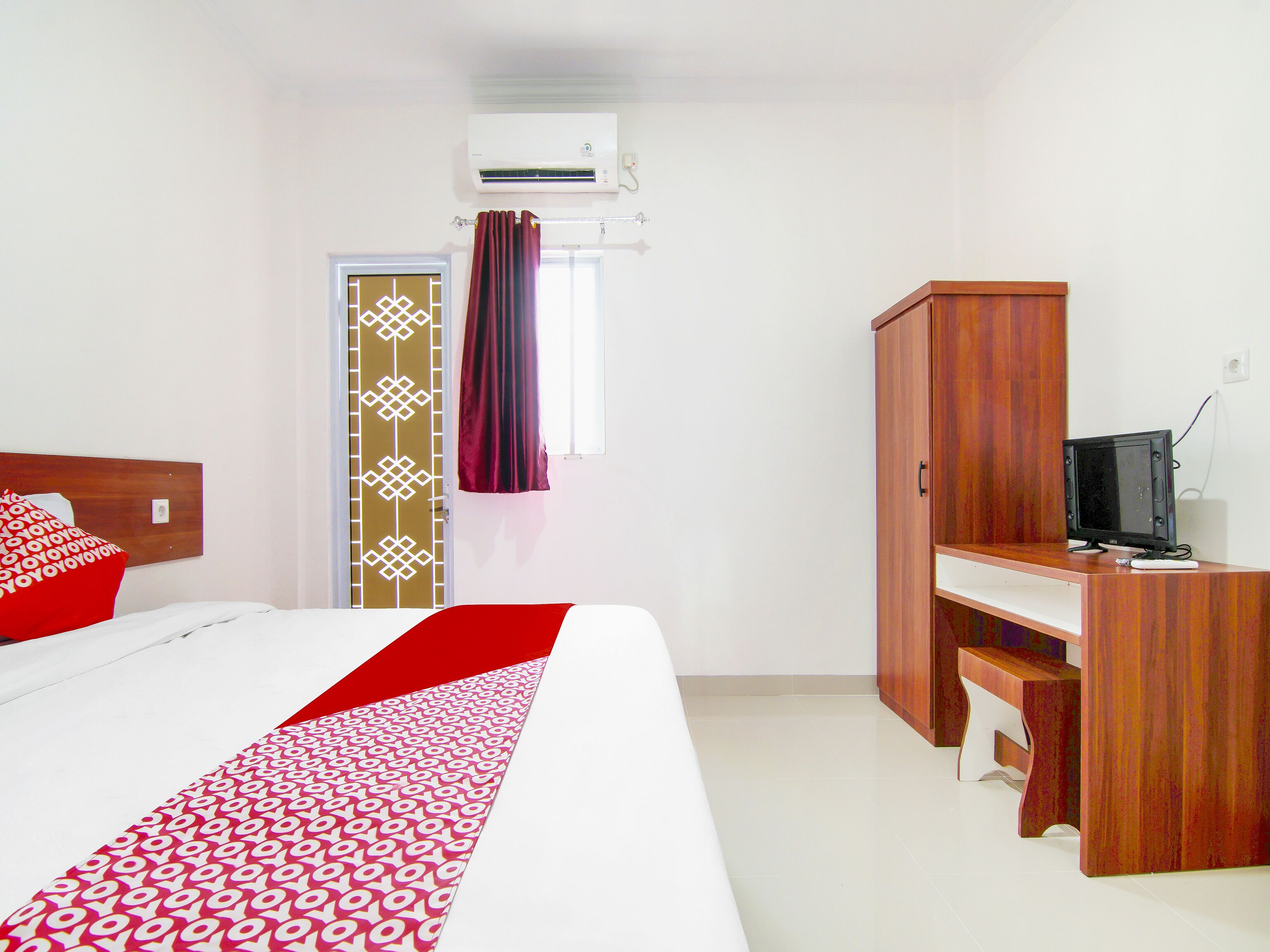 Une chambre d’hôtel équipée d’un lit, d’un bureau, d’une télévision et d’un climatiseur.
