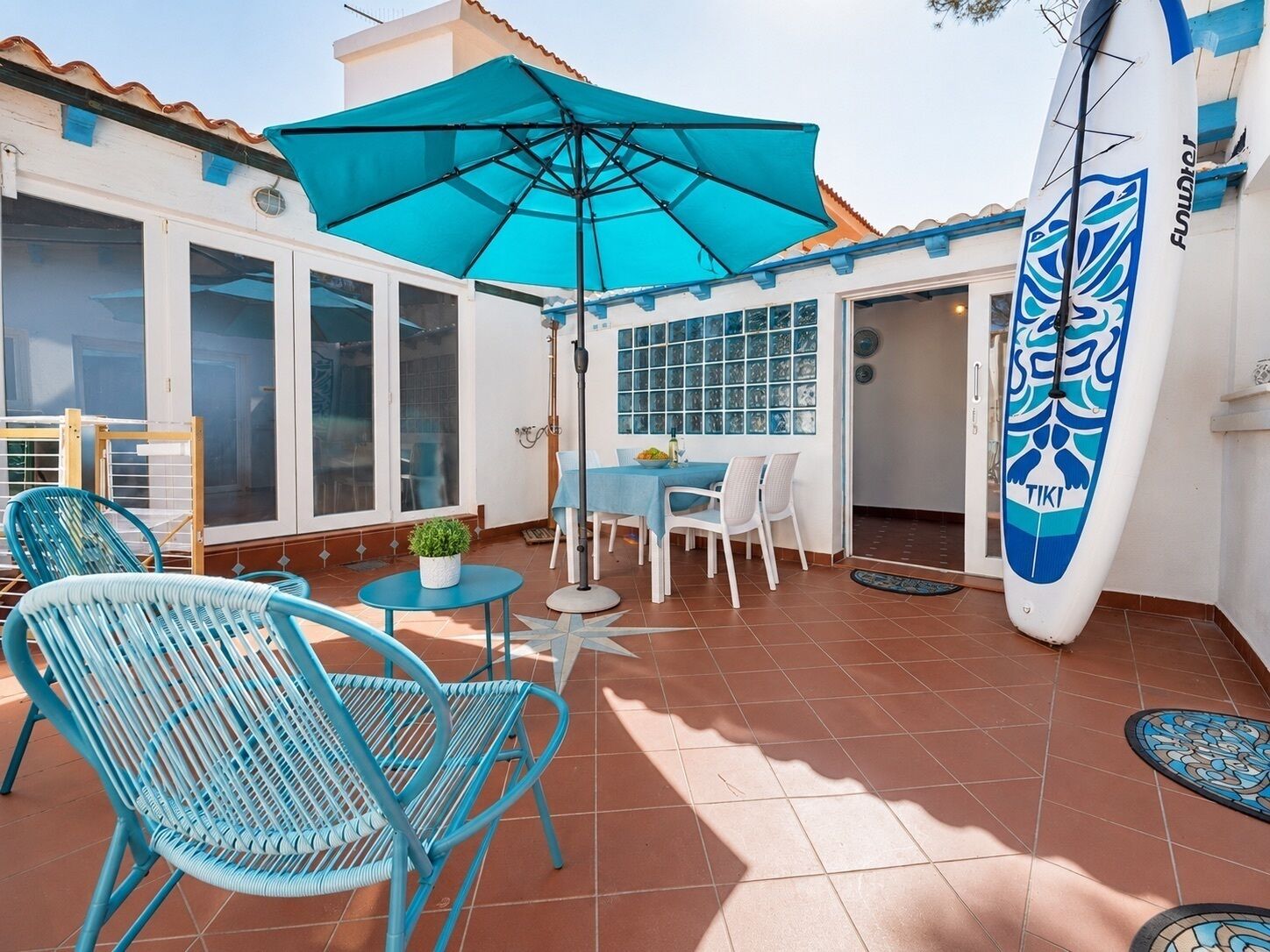 Sunny coastal patio with outdoor dining, lounge seating & surf style