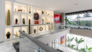 Un intérieur moderne avec une balustrade en verre, un sol en marbre et une variété d’objets d’art exposés.