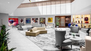 Un hall d’entrée spacieux avec un plafond haut, des sièges modernes et une variété d’œuvres d’art exposées sur les murs.