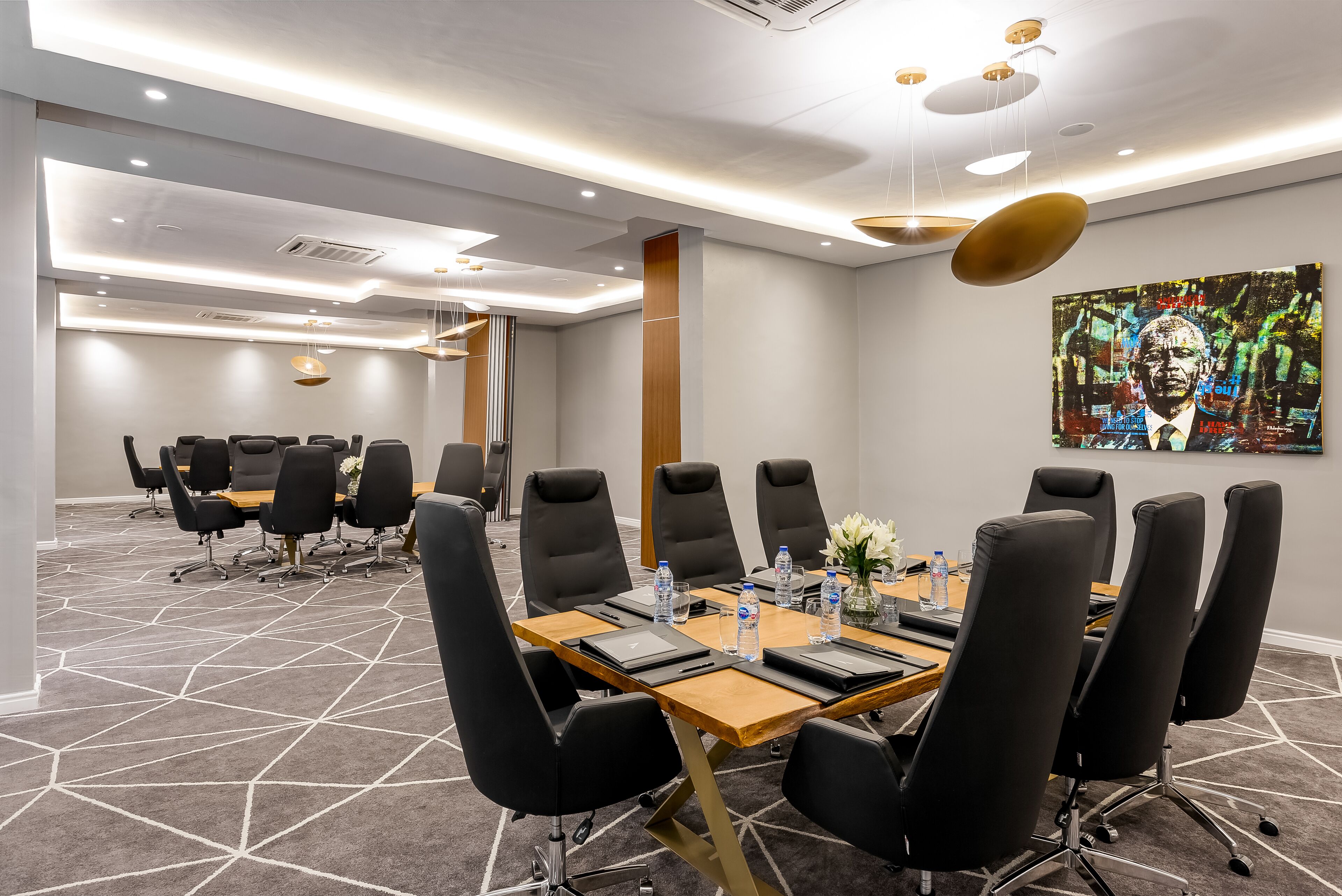 A conference room with a long table, black chairs, and a modern ceiling design.