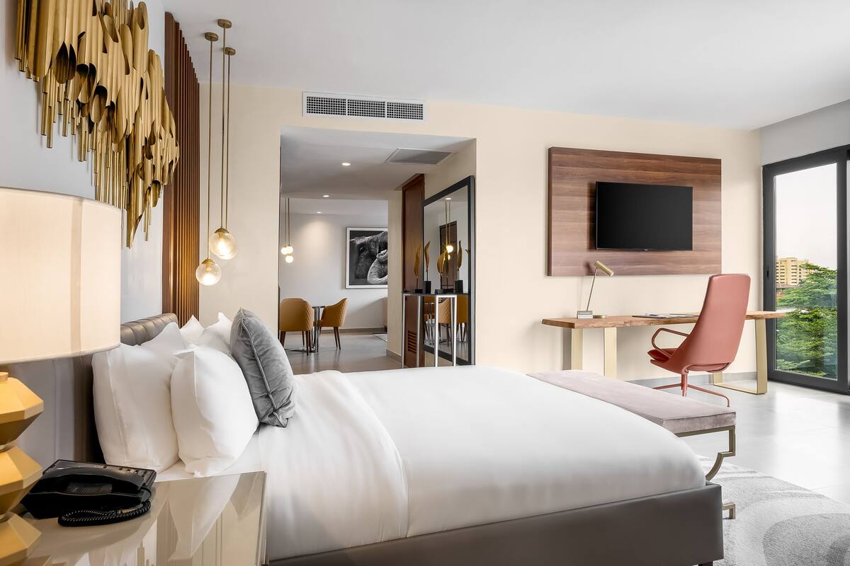 A modern hotel room with a large bed, a desk, and a TV.