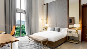Une chambre d’hôtel avec un grand lit, des tables de chevet, un bureau et une vue sur la verdure.