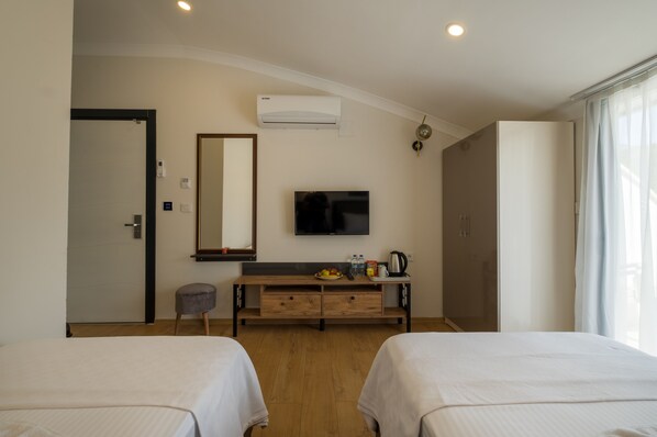 Habitación de hotel con dos camas, televisión, minibar y aire acondicionado.