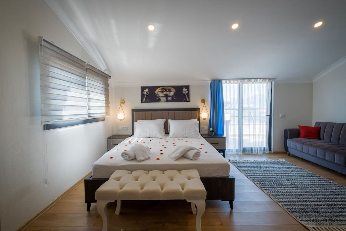 A bedroom with a bed, bench, bedside tables, and a view of the outdoors.