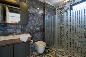 A modern bathroom with a marble sink, toilet, and shower enclosure. - Tanrise City House (Fethiye)
