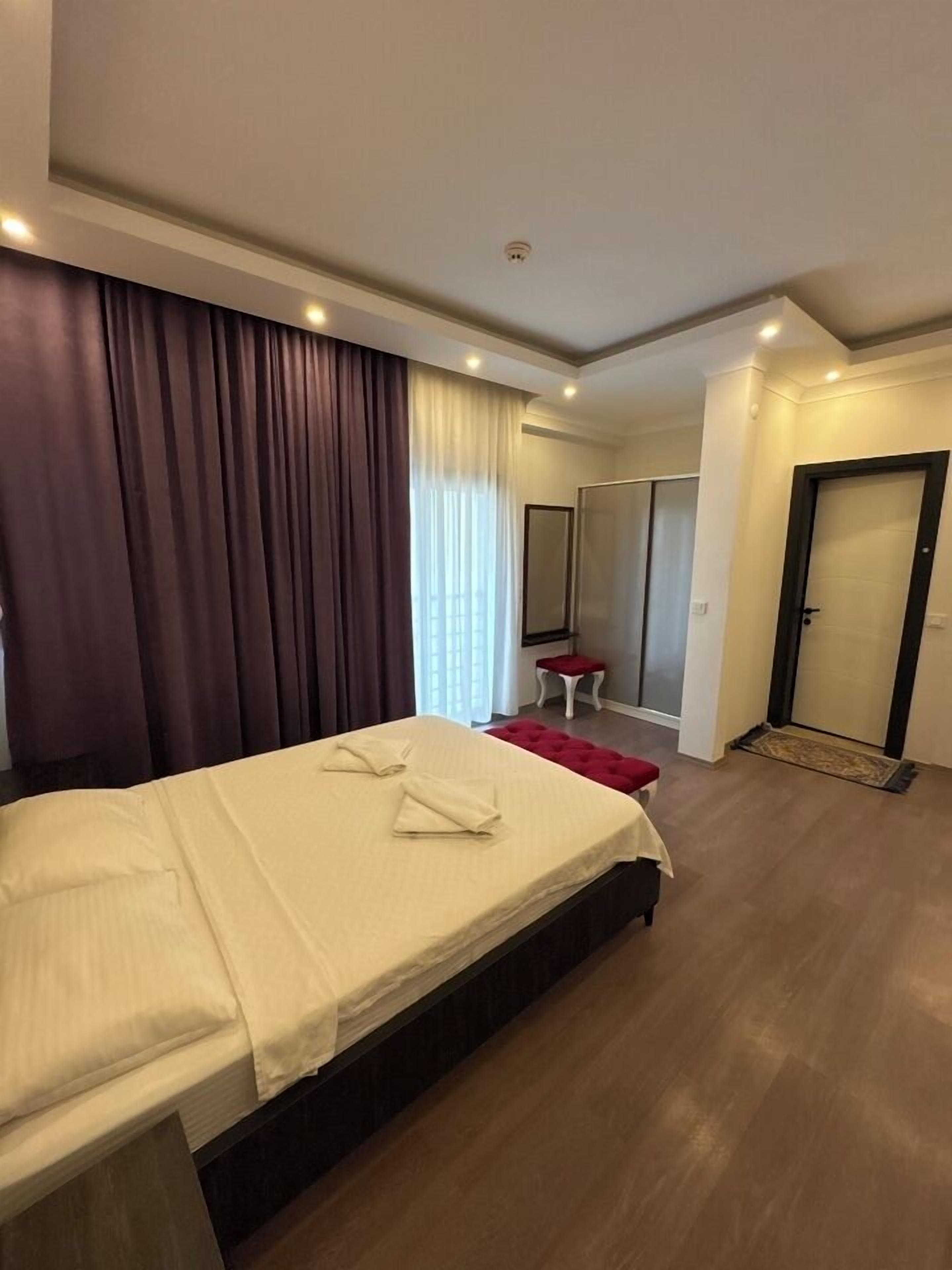 Een hotelkamer met een bed, een tafeltje, een stoel, een kledingkast en een deur.