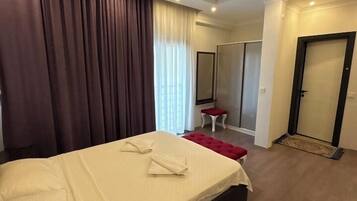 Een hotelkamer met een bed, een tafeltje, een stoel, een kledingkast en een deur.