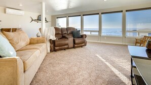A spacious living area with a leather sofa, a recliner, and a view of the ocean through large windows. - Ocean Front Condo! Spectacular Ocean Views!  Walk to Everything! (Depoe Bay)