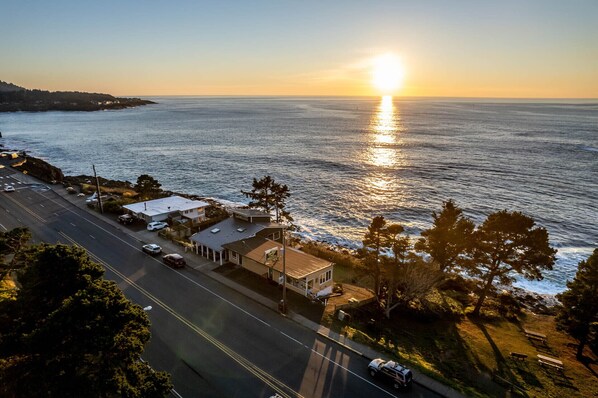 Uma estrada costeira com um edifício que tem varanda coberta e vista para o oceano.