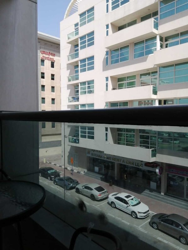 Une vue depuis un balcon donnant sur une rue où plusieurs voitures sont garées le long du trottoir.