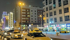 A busy urban street at night with multiple yellow taxis, illuminated buildings, and various storefronts. - AlBarsha 1 Hostel By PHM (Dubai)