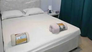 A neatly made bed with white linens, a pillow, and a rolled towel. - AlBarsha 1 Hostel By PHM (Dubai)