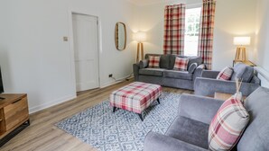 A living room with a grey sofa, a matching armchair, a plaid ottoman, and a patterned rug. - North Firbank - Culzean Castle (Maybole)