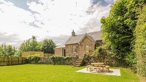 A stone house with a grassy backyard, a wooden fence, and a picnic table. - North Firbank - Culzean Castle (Maybole)