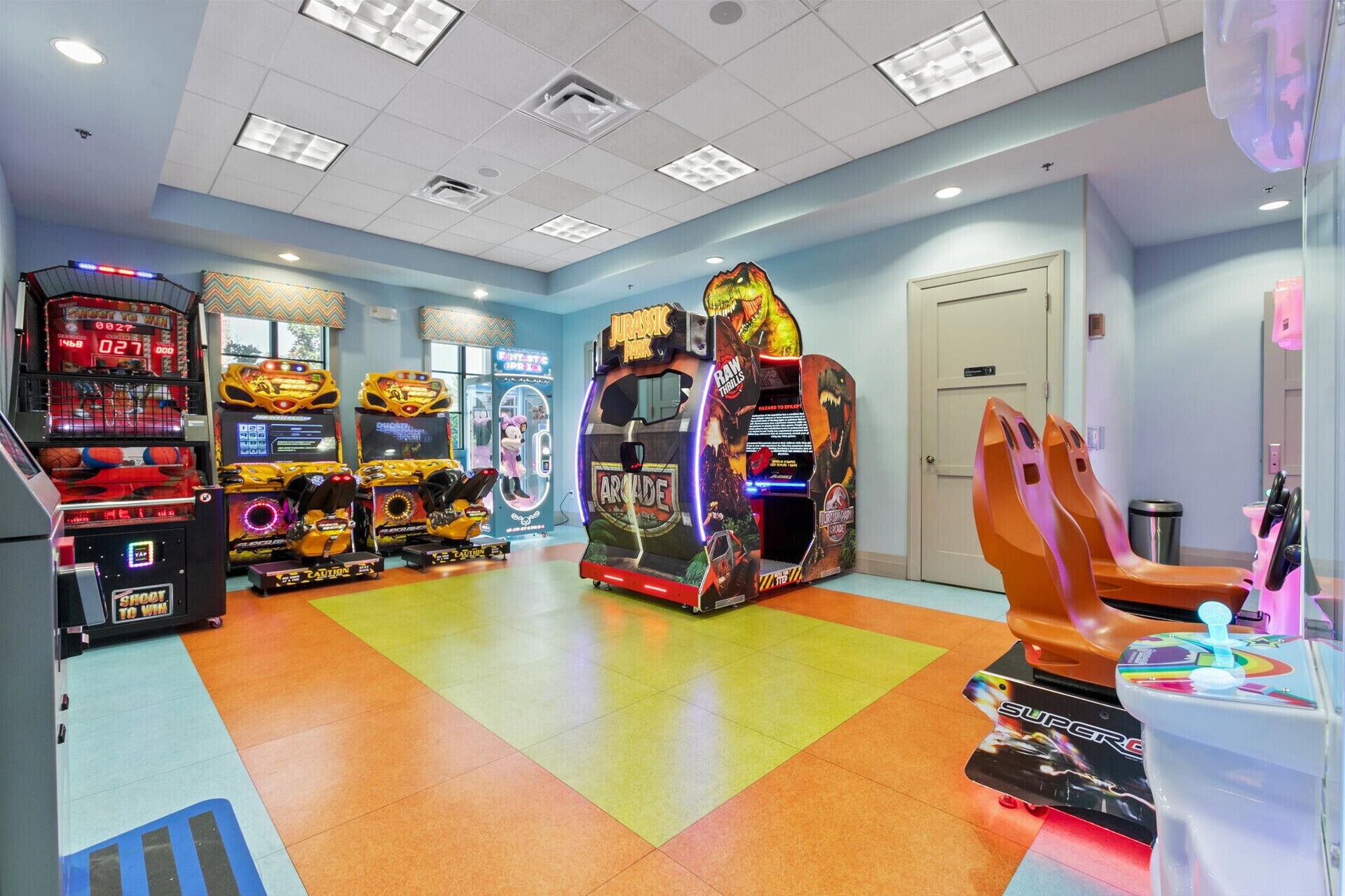 An indoor arcade with various gaming machines, a door, and a trash can.
