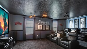 A home theater room with a large flat-screen TV, leather recliners, a popcorn machine, and a ceiling projector. - Last Minute Disney Getaway! Private Pool, Hot Tub & Game Room. Book Now! #3949 (Orlando)