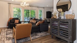 Una sala de estar moderna con un sofá gris oscuro, un sillón marrón y un aparador de madera con cajones.