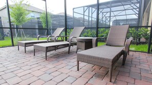 Relax in style with wicker lounge chairs and a small table, surrounded by expansive views of the surrounding greenery.