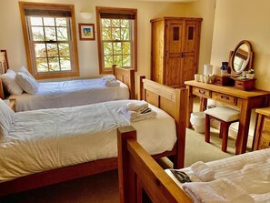 Una habitación con dos camas de madera, un escritorio de madera y un espejo.