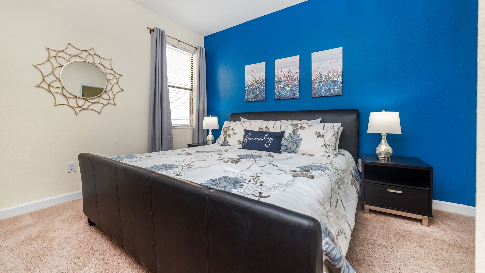 A bedroom with a bed, nightstands, a mirror, and artwork on the wall.