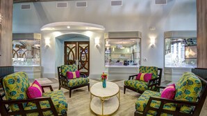 A lobby with four patterned armchairs around a central round table, a decorative mirror, and a glass display case with items. - Last Minute Disney Getaway! Private Pool, Hot Tub & Game Room. Book Now! #38570 (Orlando)