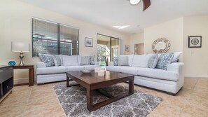 Una sala de estar con un sofá modular, una mesa de centro, una lámpara y un mueble para la televisión.