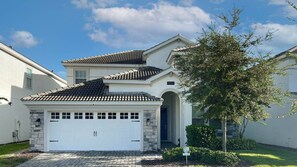 Stunning two-story residence with a symmetrical facade, surrounded by lush landscaping and a small tree.