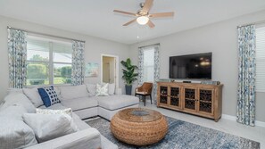 Relax in this stylish living room with a large L-shaped sofa, round coffee table, and flat-screen TV.