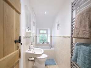 A bathroom with a wooden door, a sink, a toilet, a bathtub, and a towel rack. - Halfpenny Cottage - Two Bedroom Cottage, Sleeps 4 (Lelant)