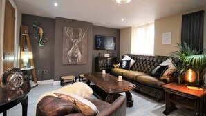 A modern living room with a leather sofa, a wooden coffee table, and a television mounted on the wall. - Janet Street Loft (3 beds) (Cardiff)