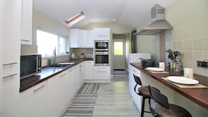 A modern kitchen with white cabinets, a wooden countertop, a built-in oven, and a stainless steel range hood. - Janet Street Loft (3 beds) (Cardiff)