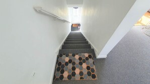 A narrow stairway with a patterned carpet leading to a landing.